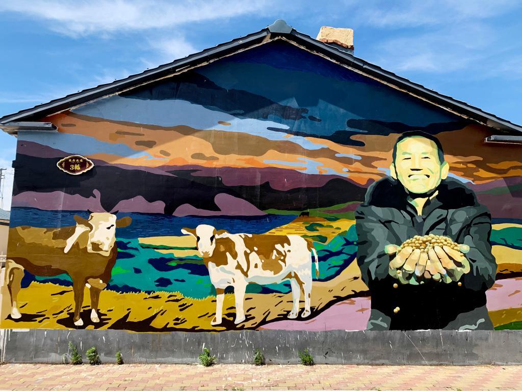 村易地扶贫搬迁小区3栋1号房屋山墙上,有一幅色彩绚丽,描绘丰收的墙绘