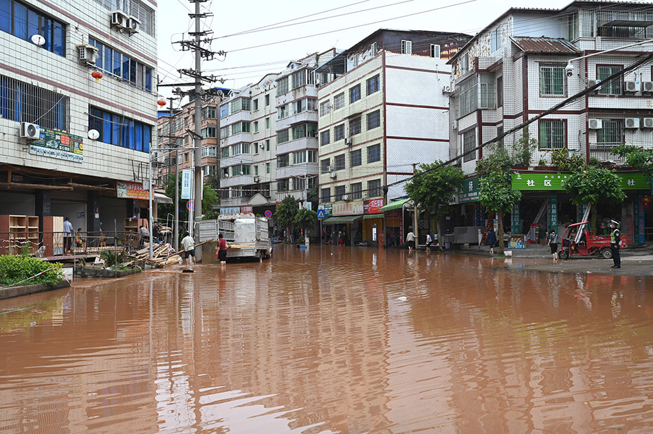 2022年4月24日,四川省内江市东兴区田家镇,街道积水严重,居民正在清理