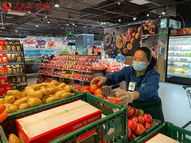 北京CBD核心区域的一家盒马连锁店内,店员正在补充蔬菜供应。人民网 尹星云摄