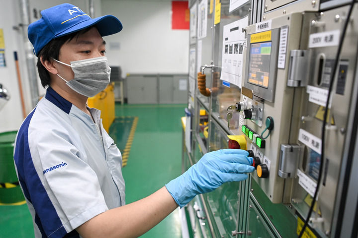 松下能源(无锡)有限公司的工人在电池组装车间生产线上操作机器(7月5