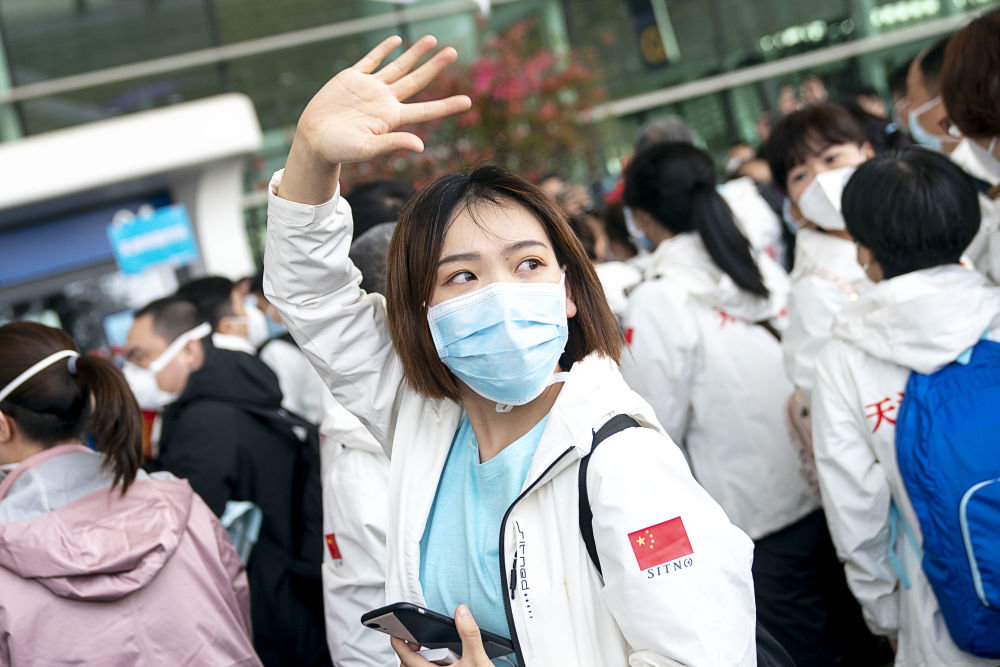 2020年3月17日，在武汉天河机场，完成援鄂任务后随队撤离的天津国家紧急医学救援队队员张硕向送行的人们挥手告别。新华社记者 熊琦 摄