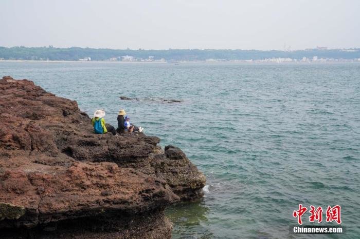 广西北海市涠洲岛景区，游客在南湾鳄鱼山的火山遗迹景点观景拍照。 王以照 摄