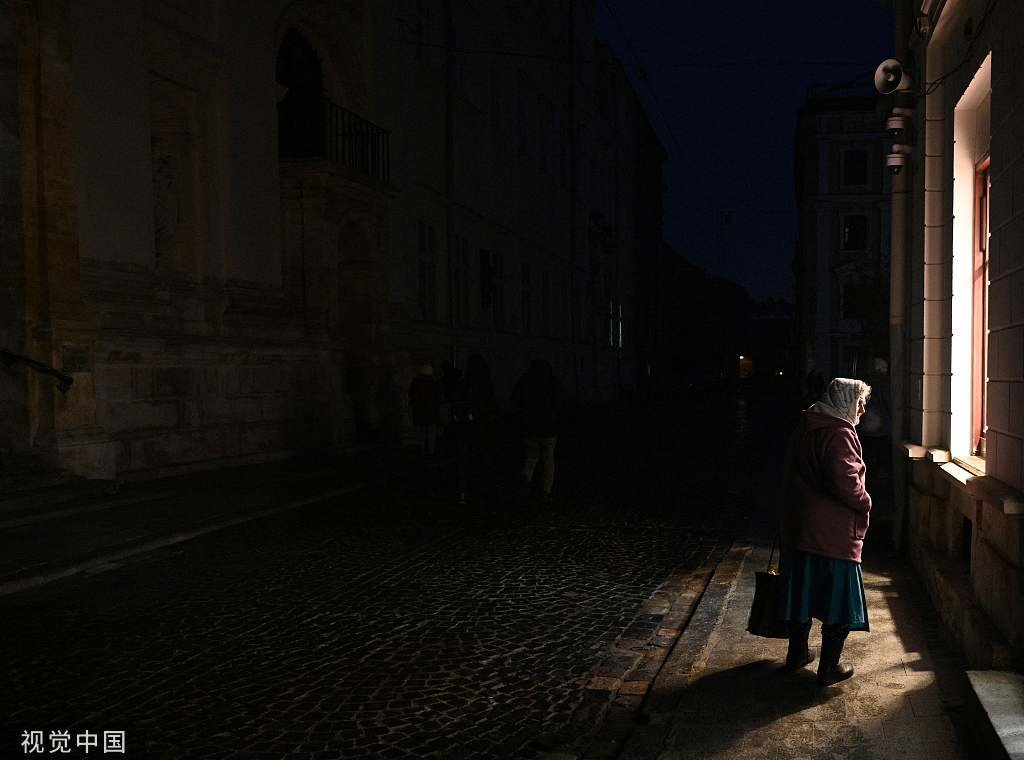 当地时间2022年11月23日，乌克兰利沃夫，一名妇女在停电期间走在街上。