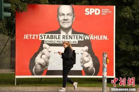 2021年8月26日，一名行人经过柏林街头的社民党总理候选人朔尔茨的竞选展板。中新社记者 彭大伟　摄