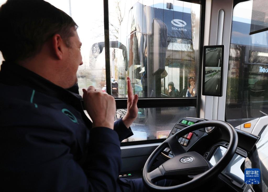 12月7日，法国巴黎大众运输公司公交司机“驾驶”中车电动制造的自动驾驶客车途中与会车司机打招呼。新华社记者 高静 摄