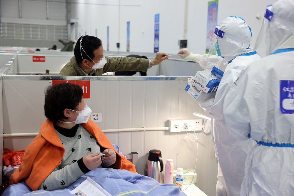 ↑4月6日，在上海临港方舱医院，来江苏的医护人员在帮感染者查看体温。新华社发（华山医院 供图）