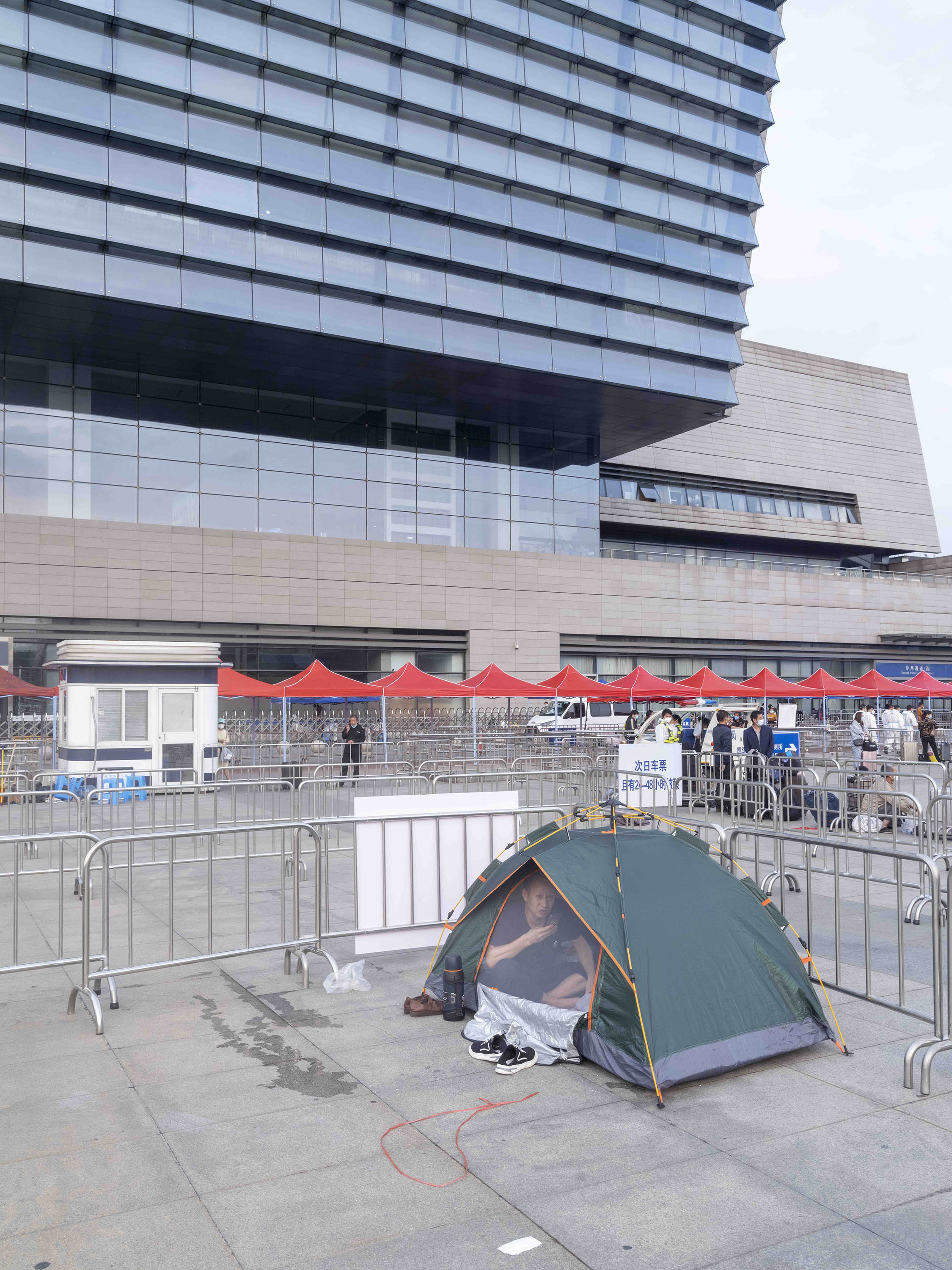 2022年5月26日，虹桥火车站前，一名男子在临时搭起的帐篷中休息。