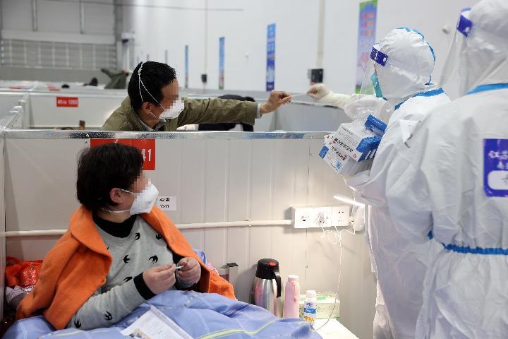 4月6日，在上海临港方舱医院，来自江苏的医护人员在帮感染者查看体温。新华社发（华山医院 供图）