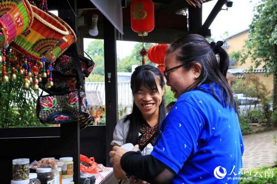赵仁芹（左）热情地向游客介绍着自家的特色农产品。人民网 刘怡摄