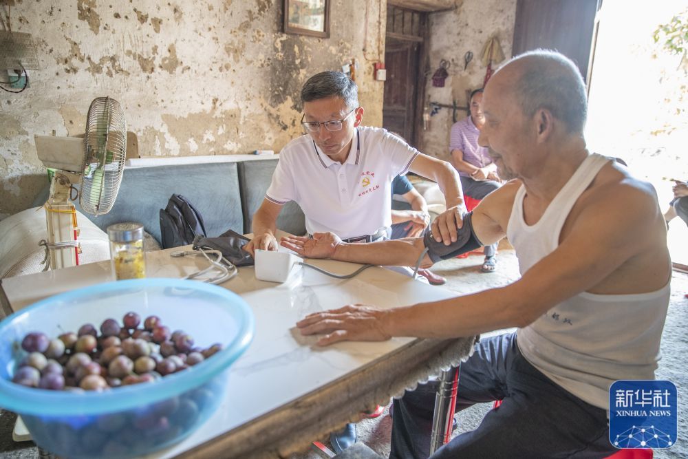 8月11日，在重庆市巫溪县田坝镇田坝村，驻村第一书记蒋在强（左）在入户走访时为村民做健康监测。新华社记者 黄伟 摄