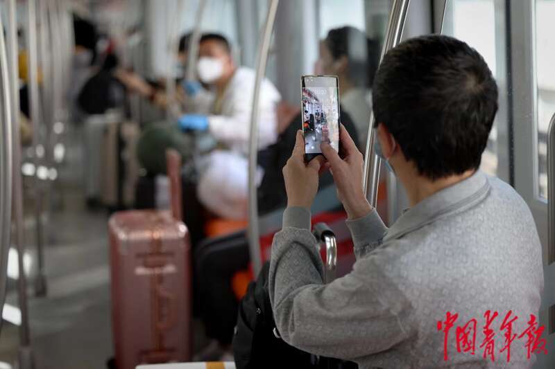 5月22日，上海地铁3号线，一名乘客拿起手机拍摄地铁3号线复运首班车内的场景。中青报·中青网记者 李强/摄