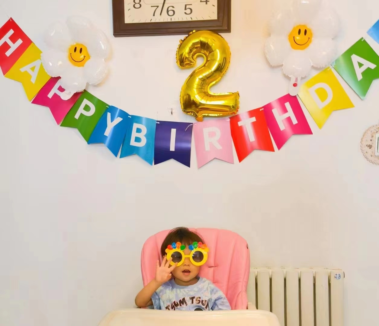 5月2日,爷爷奶奶为小予乐在家中布置的生日墙,小予乐戴着卡通眼镜坐在