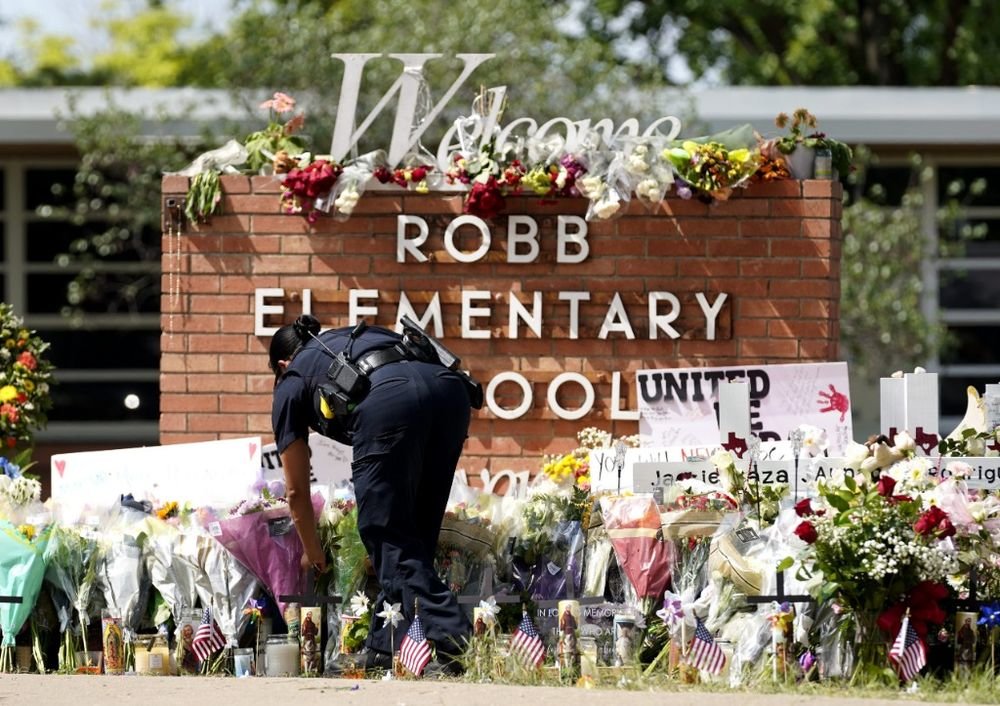 2022年5月27日，警察在美国得克萨斯州南部尤瓦尔迪市发生枪击事件的小学外摆放花束。新华社记者吴晓凌摄