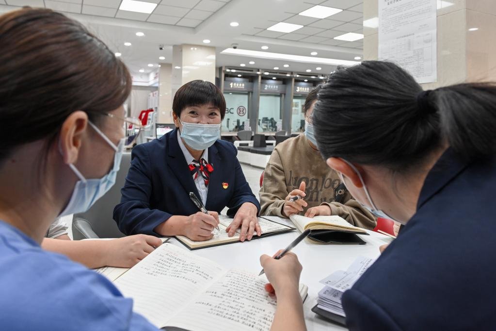 在中国工商银行新疆乌鲁木齐的一处营业网点，李鹏与员工进行业务交流（2022年9月24日摄）。新华社记者 郝建伟 摄