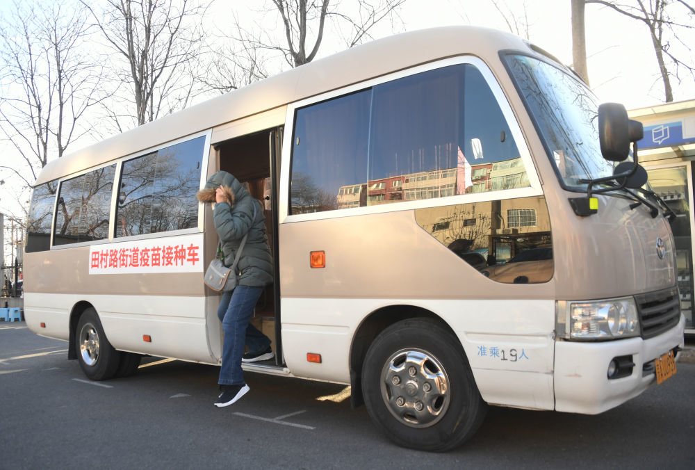 12月17日,在北京市海淀区田村路街道新冠疫苗临时接种点,一名老人从“暖心巴士”下车准备接种新冠疫苗。