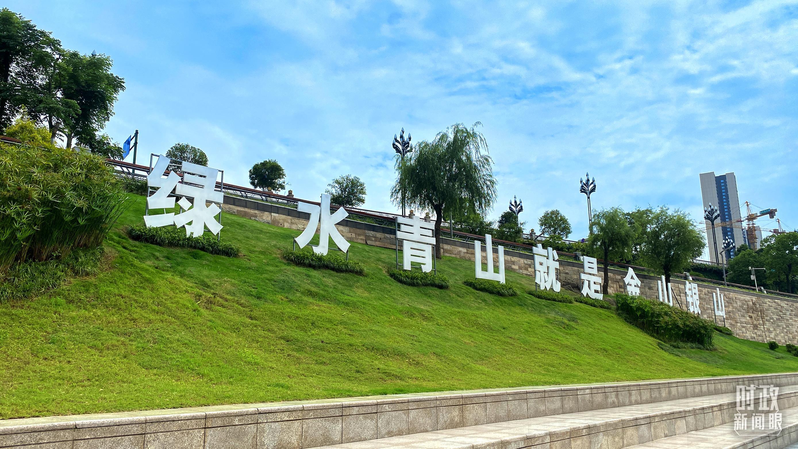 △三江口岸边，“绿水青山就是金山银山”标语醒目。（总台央视记者李辉拍摄）