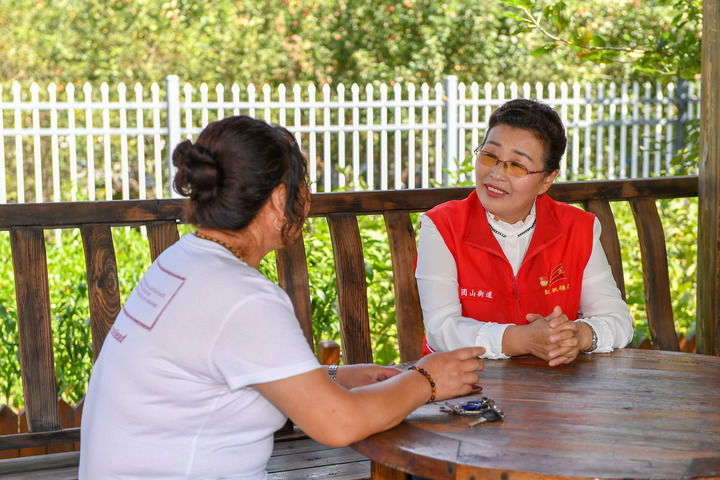 8月24日,吴亚琴(右)与团山街道长山花园社区的楼栋党支部书记李杰聊天
