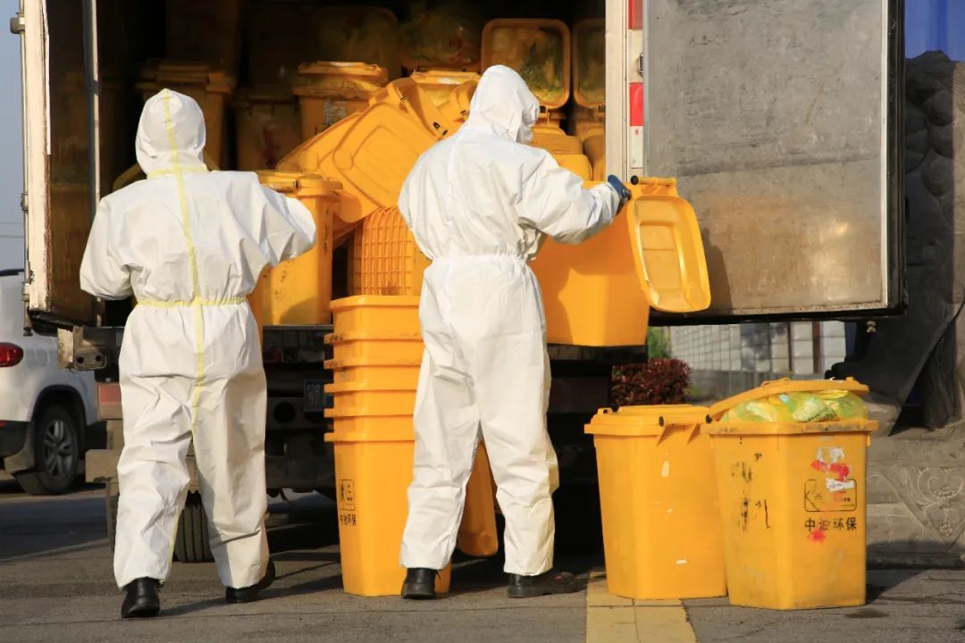 2020年3月，湖北省襄阳市，工作人员在向医疗废物转运车上搬运废弃的一次性防护口罩。