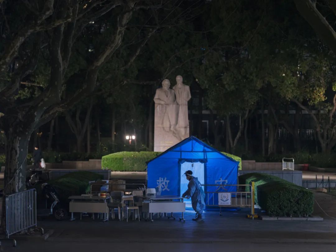 3月14日晚，上海市黄浦区复兴公园，核酸检测结束后，一名防疫人员收拾桌椅。西野/摄