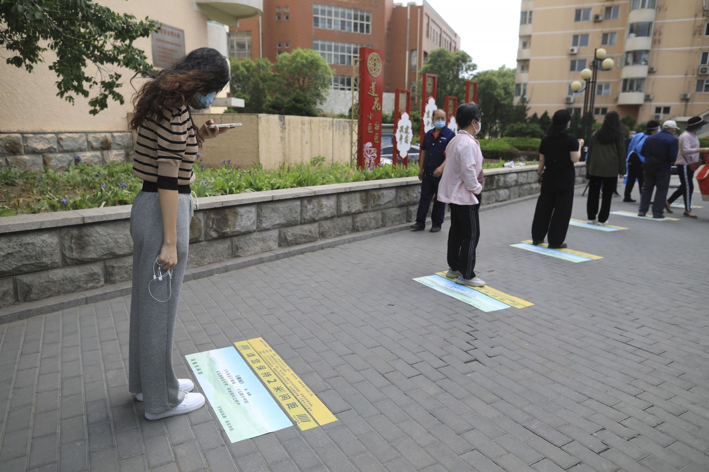 5月5日，海淀区羊坊店街道莲花小区，一位女士在排队时拍摄地上的古诗。 新京报记者 浦峰 摄