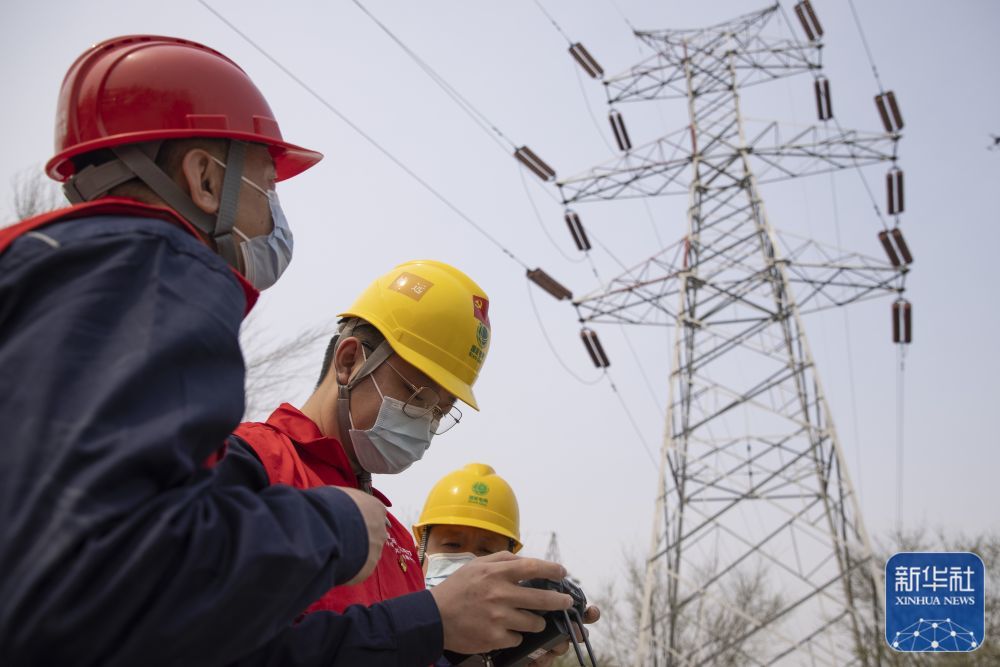 4月29日,梅宏刚(左一)与同事一起利用无人机对供电设备进行特殊巡检。新华社记者 张涛 摄