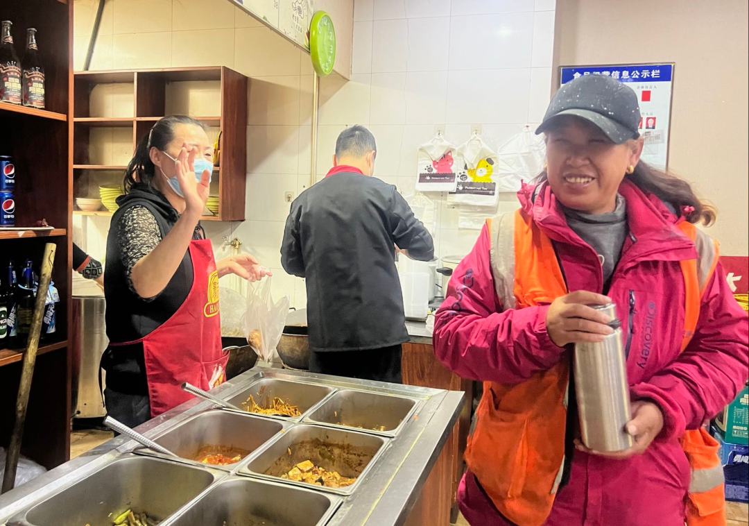 10月21日，环卫工常红梅拿着王林珍递给她的热水杯笑着打招呼告别。新华社记者 柴婷 摄