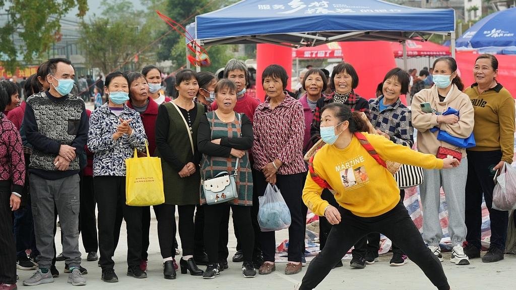 2022年11月22日，广西柳州，在融水苗族自治县三防镇乃文村，一名妇女在抛绣球活动中接绣球。 视觉中国 图