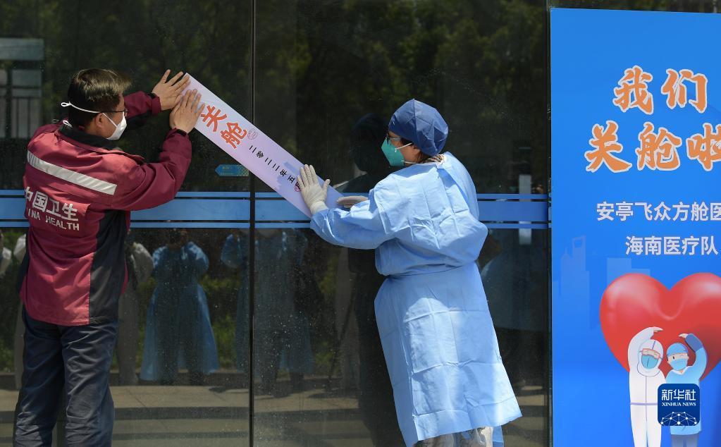 5月4日，海南省医疗队领队李文秀（左）和嘉定区卫健委工作人员一起为安亭飞众方舱医院大门粘贴关舱封条。新华社记者 李贺 摄