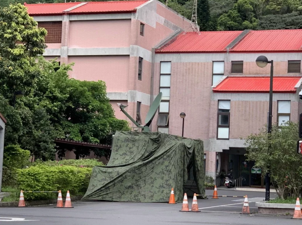行控中心门口已有编组在台湾军队防空导弹部队下属的能在行进间进行卫星通讯的二代卫星通讯车在伪装网下作业 图片来源：《联合报》
