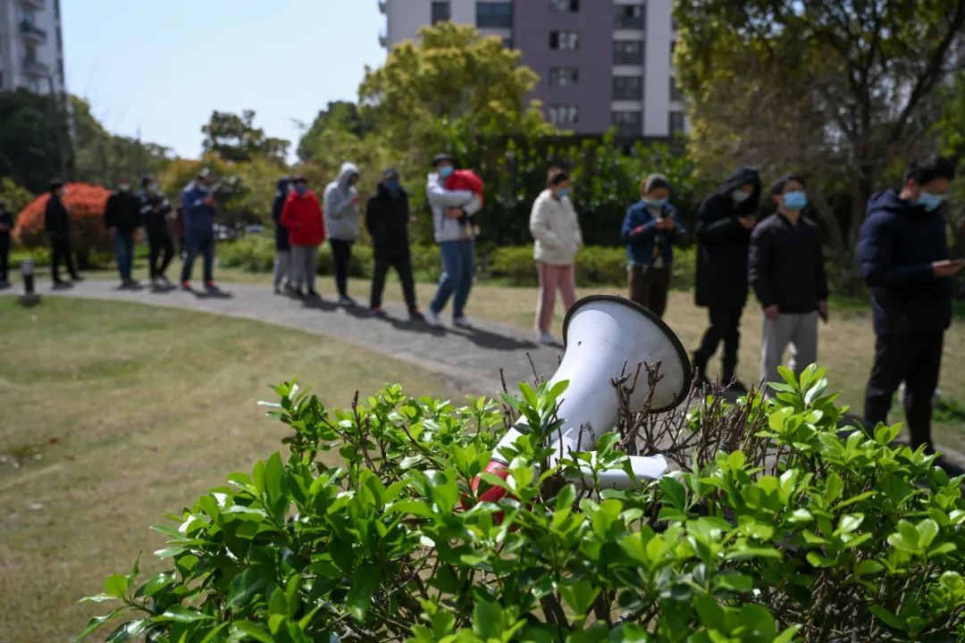 3月23日，上海市某封控小区，居民排队等候做核酸检测，喇叭里不停播放着“保持一米安全距离”的提醒。朱伟辉/摄