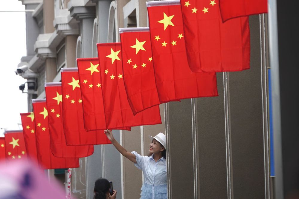 △10月1日，一名市民在广西南宁市朝阳广场步行街与悬挂的国旗合影。