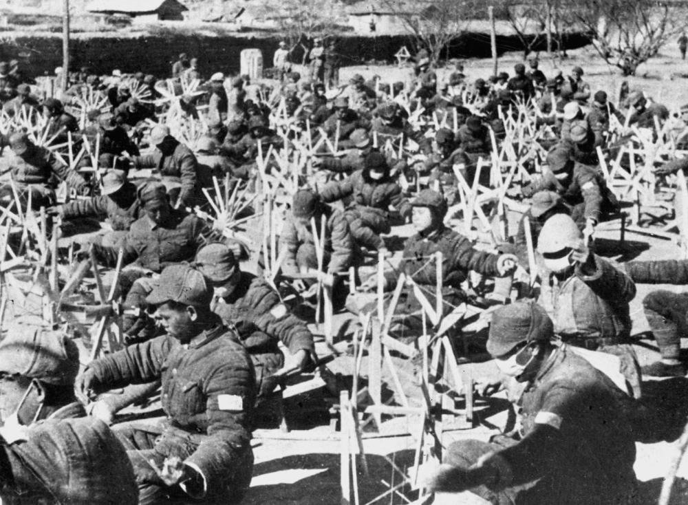 ↑八路军战士坐在纺纱车前纺纱（资料照片）。