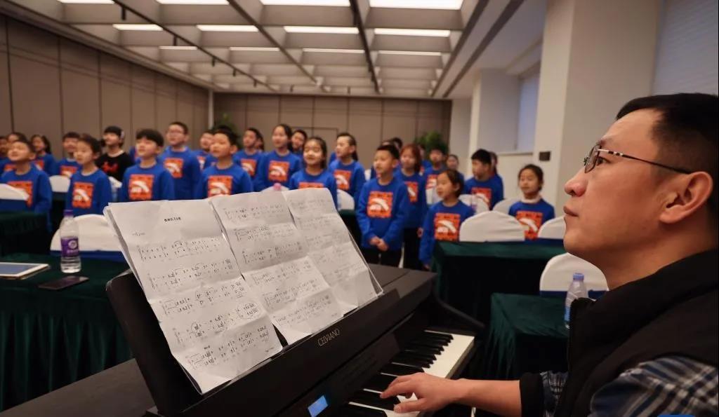 保定学院音乐舞蹈学院声乐教师王金山（右）与马兰花儿童合唱团在酒店会议室排练。 （摄影：许雅楠）