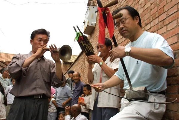 田青（右一）在山西左权红都村考察，与民歌手石占明一起演奏左权小花戏。（2003年）