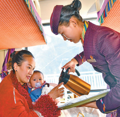 青藏铁路延长线拉日铁路Z8801次列车上,乘务员在为乘客倒水。新华社记者 张汝锋摄