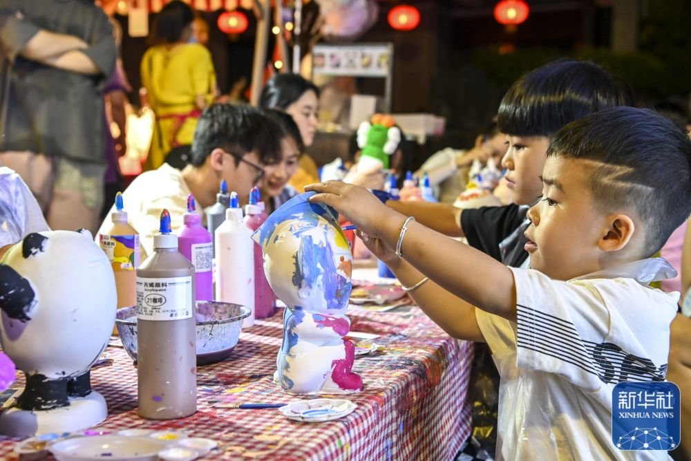 10月1日，在南宁一处夜市，小朋友为石膏模型上色。新华社记者 曹祎铭 摄