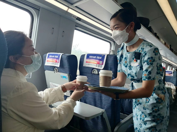 7月27日，列车员依波逢为旅客递上一杯咖啡。新华网记者 侯强 摄