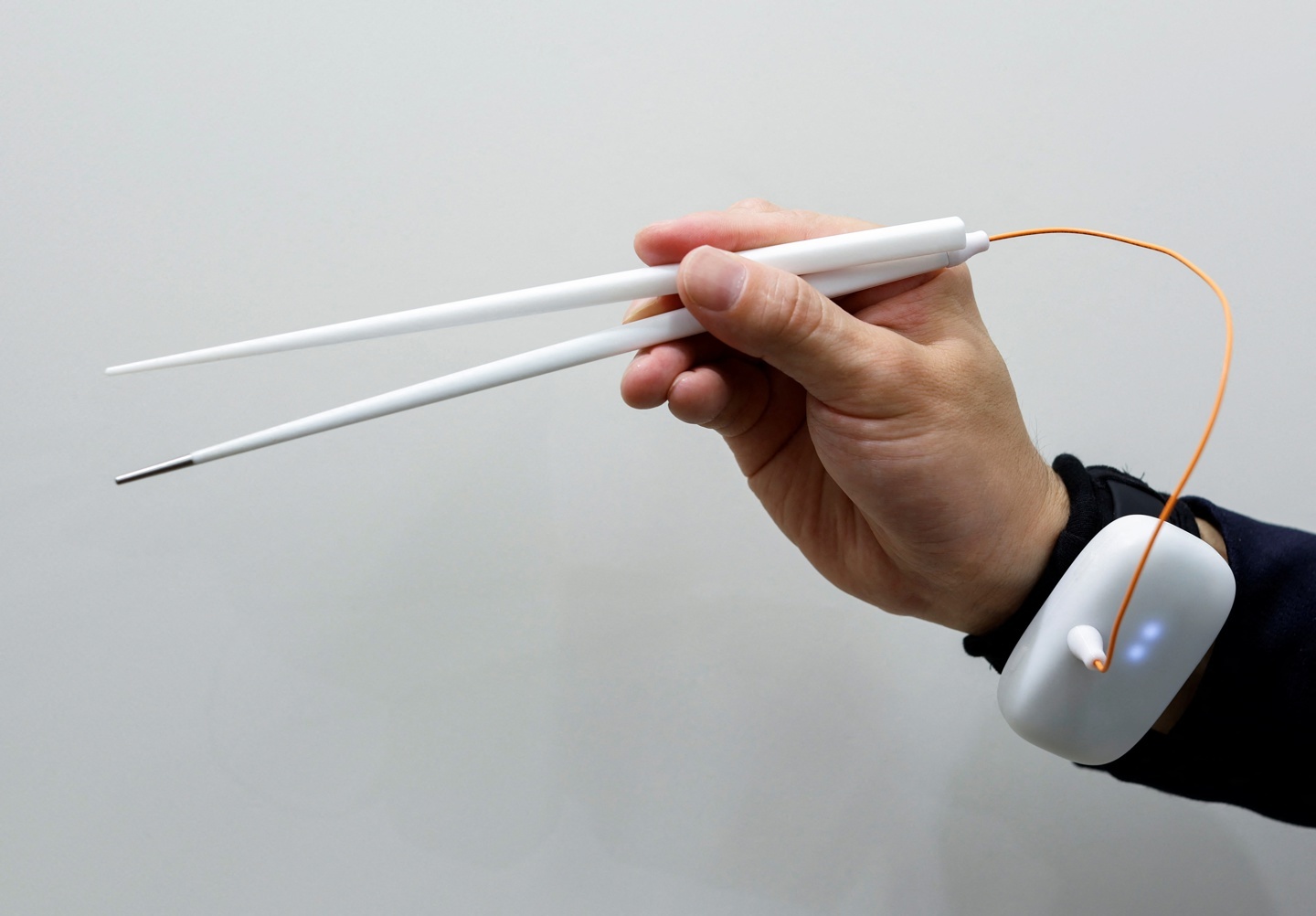 An employee of Kirin Holdings demonstrates chopsticks that can enchance food taste using an electrical stimulation waveform in Tokyo