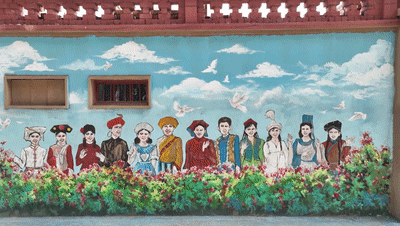 △当地的文化墙绘上,专门呈现了新城西门村和十八洞村元素。(总台记者曹江拍摄)