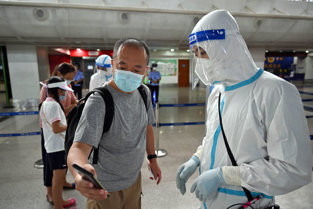 ↑8月9日，三亚凤凰国际机场工作人员在查验游客的核酸检测阴性证明。
