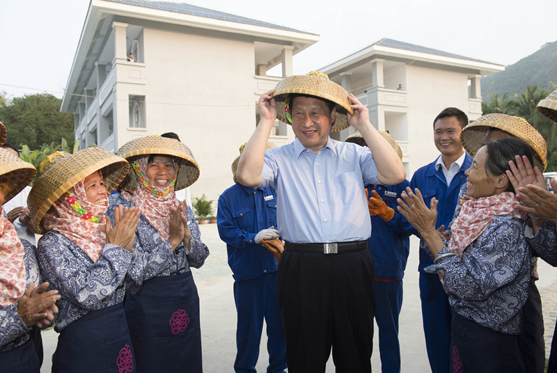 2013年4月9日，习近平总书记在亚龙湾兰德玫瑰风情产业园高兴地戴上黎族群众递上的竹笠。