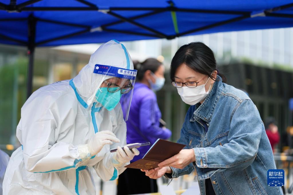  在北京市朝阳区八里庄街道一处核酸检测点，来自北京一家纺织集团有限公司的志愿者、在职党员白一江（左）在为一位检测者登记身份信息（5月8日摄）。 新华社记者 鞠焕宗 摄