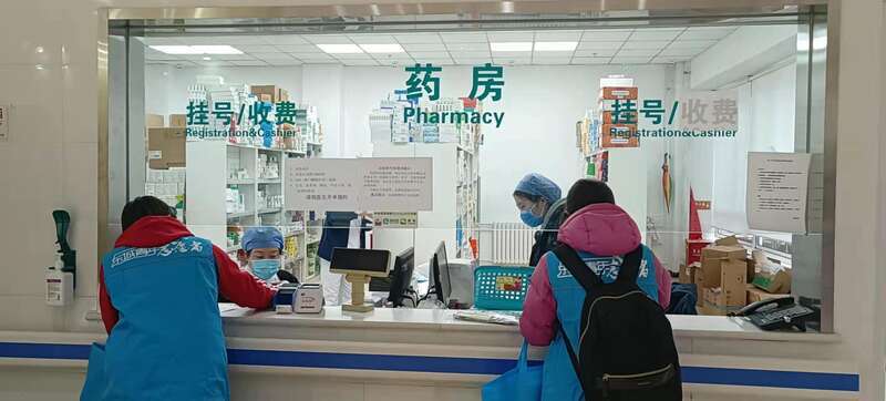 志愿购物组组员为居民排队代购药物。(石玉龙/摄)