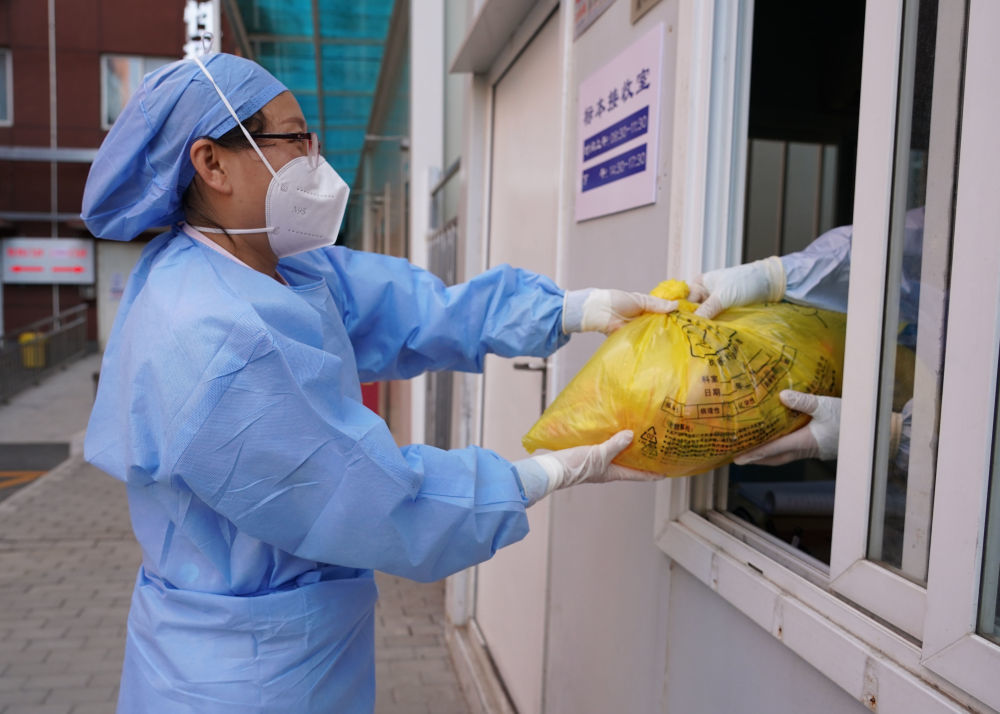 5月25日，在北京市上地医院，护师将取回的隔离酒店人员的核酸样本交给样本接收室医务人员。新华社记者 任超 摄