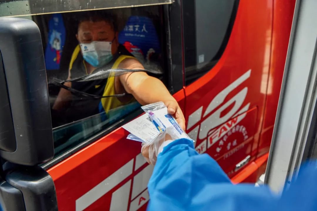 8月8日，海南海口市新海港的工作人员为离岛货车司机发放新冠抗原检测试剂。摄影/本刊记者 骆云飞