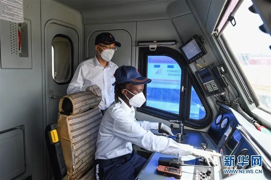 2021年3月22日，在肯尼亚首都内罗毕，蒙内铁路指导司机杨明和他的肯尼亚女徒弟康西莉亚在机车内进行发车前的检查工作。新华社记者 李琰 摄