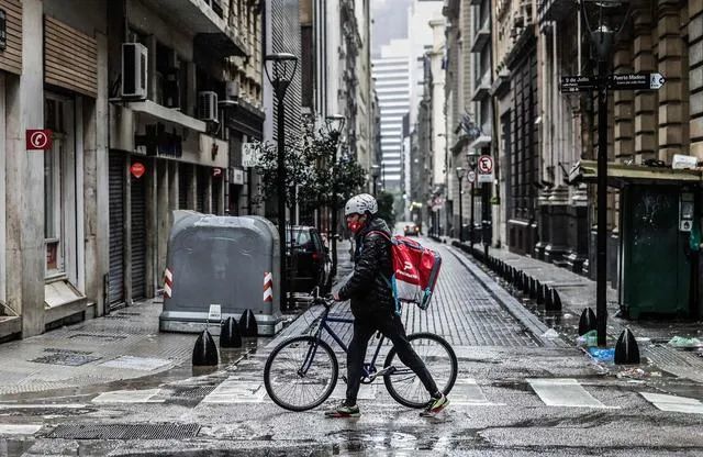 ▲2021年5月22日，阿根廷布宜诺斯艾利斯一名送餐员走过空旷的街道。 图/新华社