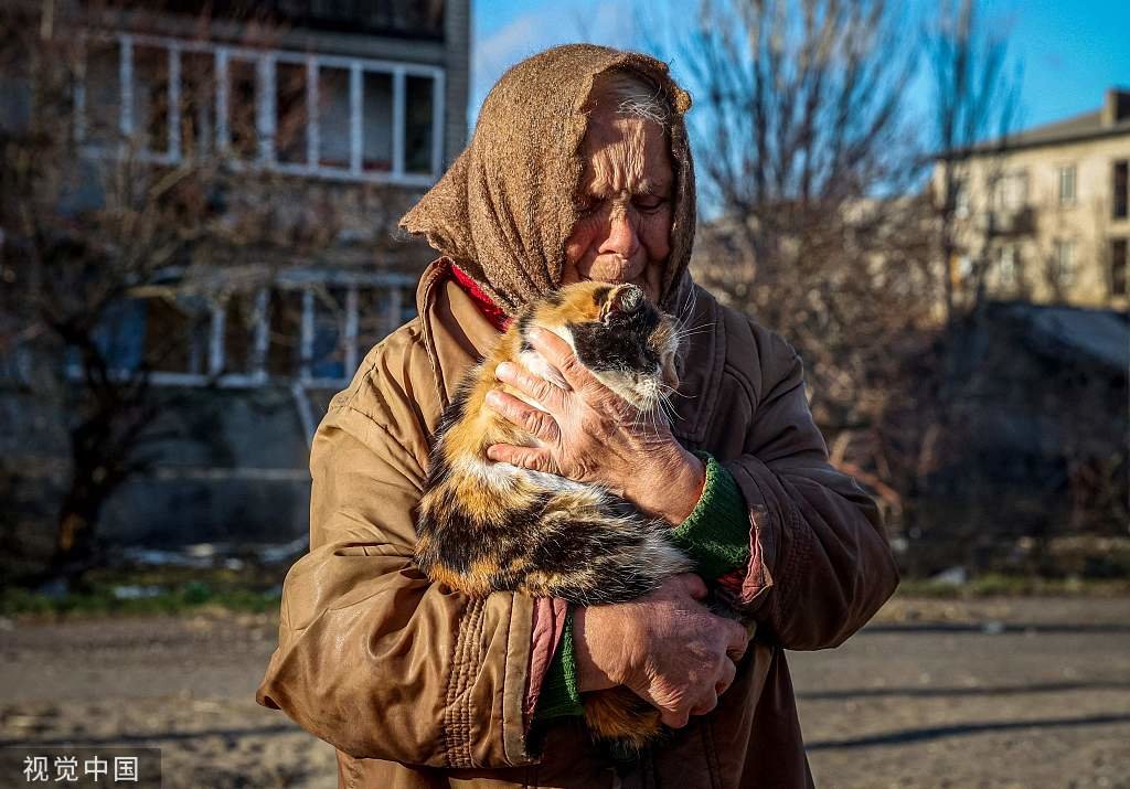 当地时间2022年12月15日，顿涅茨克莱曼，80岁的老人抱着一只猫，她住在一座受损的建筑里，那里没有电、水和暖气。