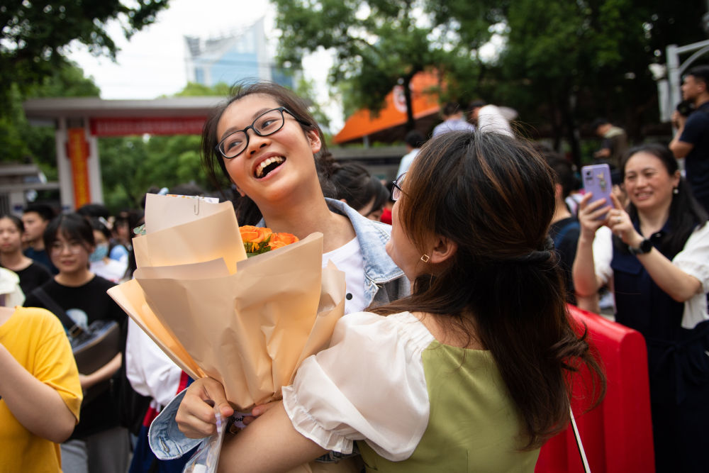 ↑6月9日，一名考生（左）在湖南省长沙市一中考点外从家长手中接过鲜花。新华社记者 陈思汗 摄