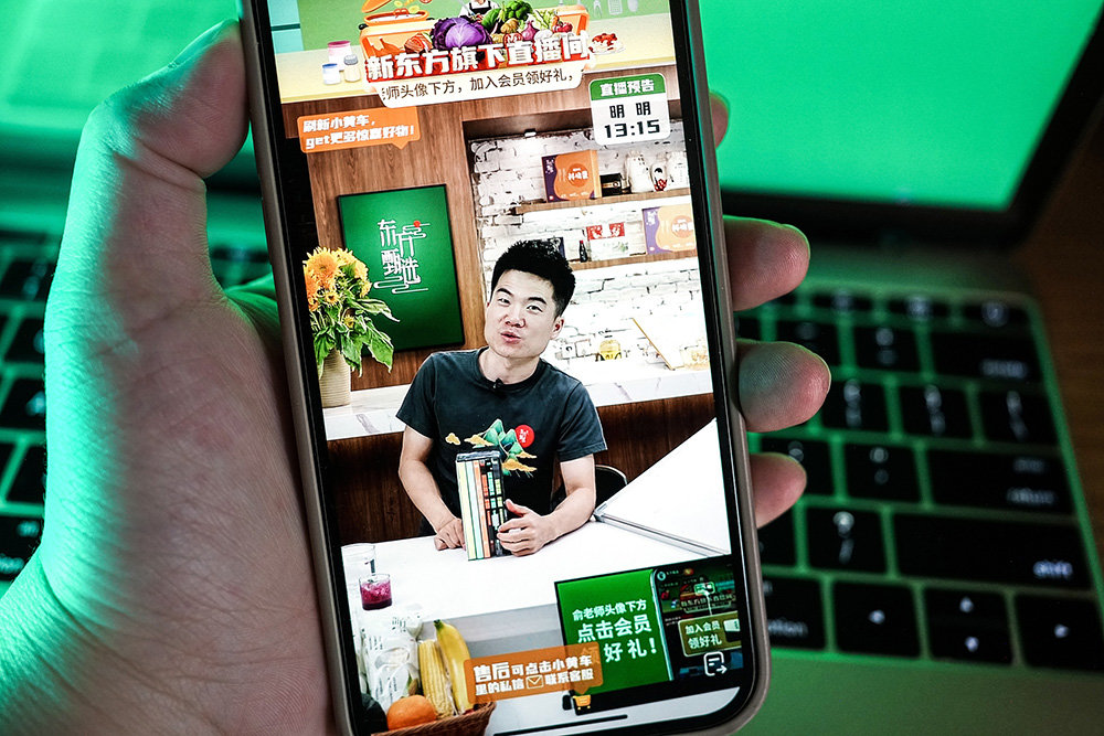 市民在手机上观看东方甄选抖音直播间,主播董宇辉正在卖书。视觉中国 图